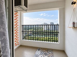 Una habitación con un ventanal grande, baranda de metal negro, alfombra estampada y una estantería de pared con una lata.