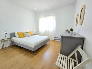 Un dormitorio moderno con cama, mesitas de noche, un escritorio y una silla.