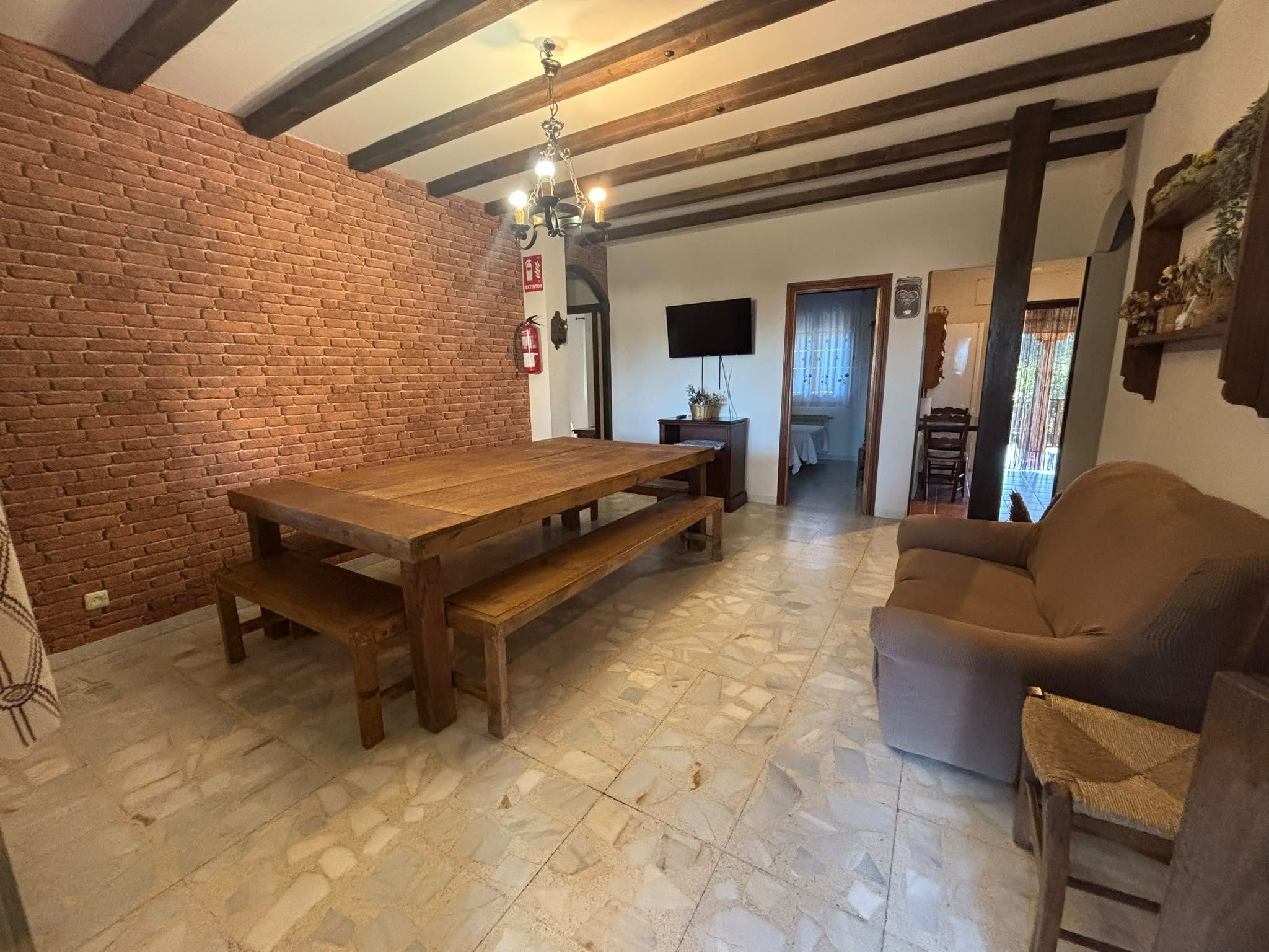 Un comedor con pared de ladrillo, una mesa de madera y un sofá marrón.