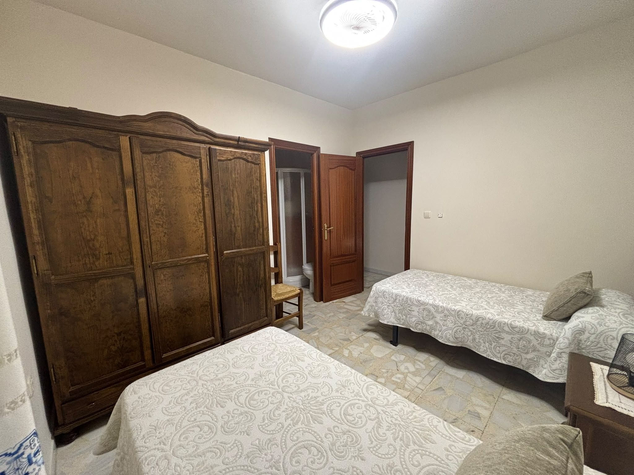 Un dormitorio con armario, cama y silla.