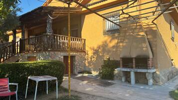 Un edificio con fachada de piedra, balcón de madera y zona de barbacoa.