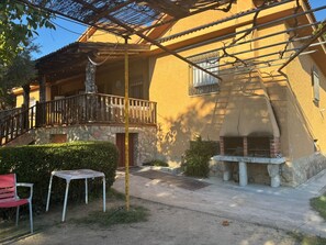 Un edificio con fachada de piedra, balcón de madera y zona de barbacoa.