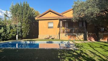 Una casa a due piani con piscina, una scala in pietra e un balcone.