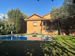 Una casa a due piani con piscina, una scala in pietra e un balcone.