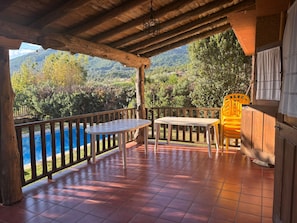 Un'area esterna coperta con piscina, mobili in legno e vista su un paesaggio montano.