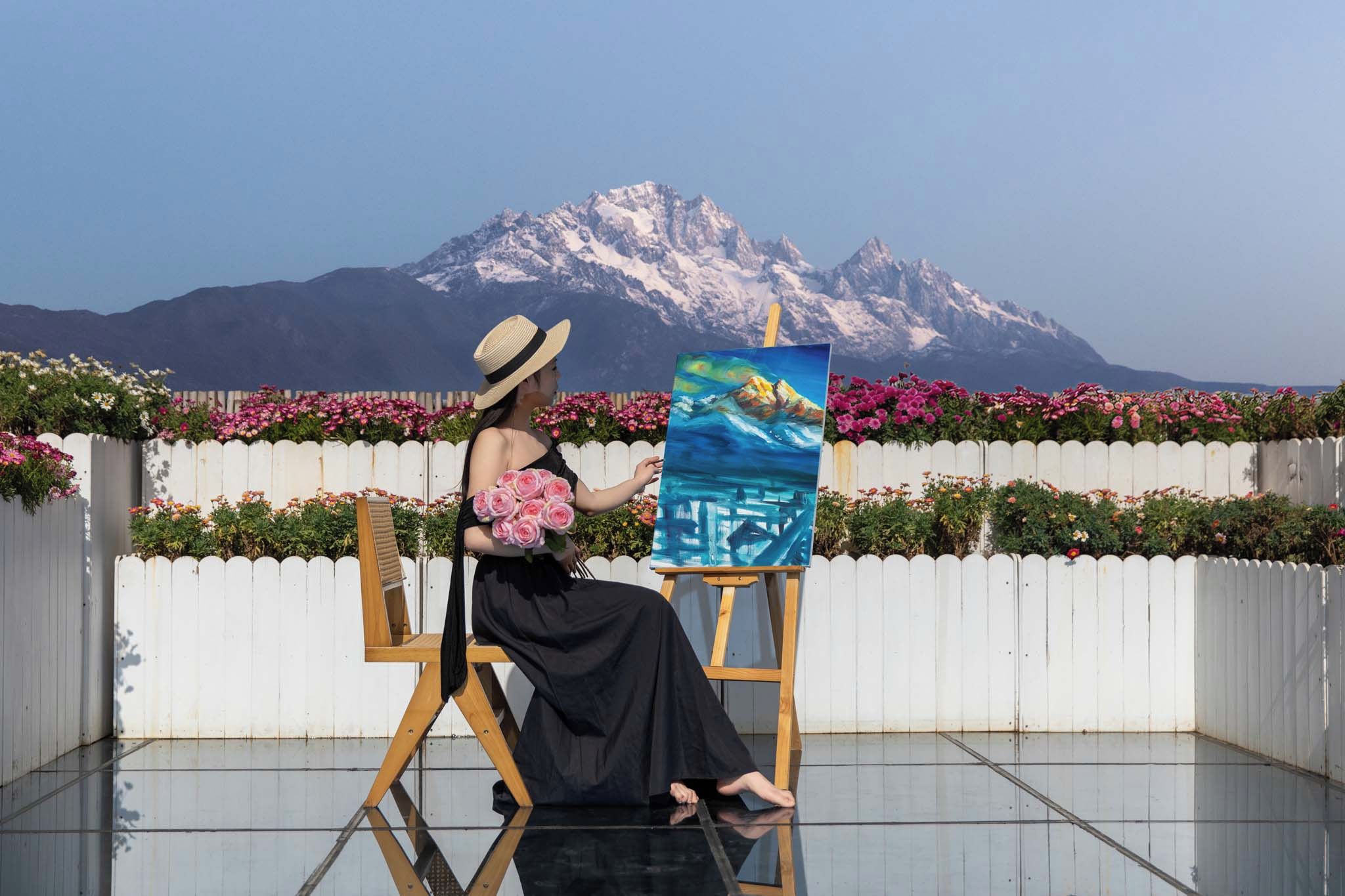Une personne peignant un paysage avec une montagne en arrière-plan.