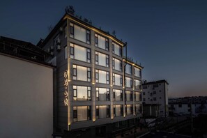 Un edificio de hotel de varios pisos con ventanas iluminadas y un letrero con caracteres chinos.