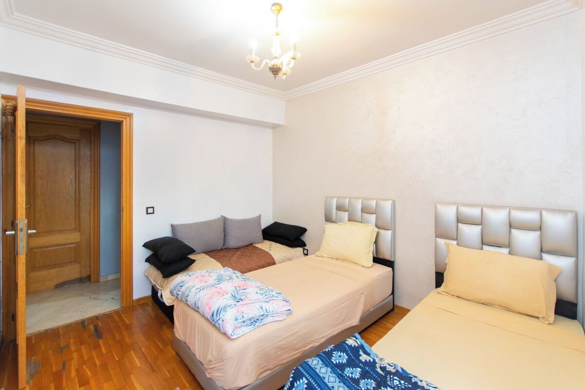 A bedroom with two beds, a wooden door, and a chandelier.