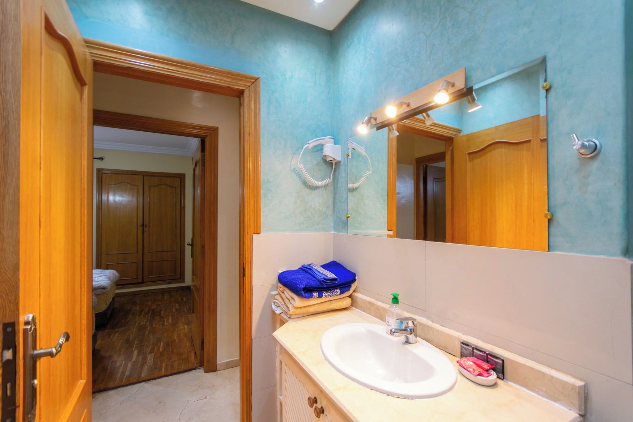 A bathroom with a sink, mirror, and towel rack.