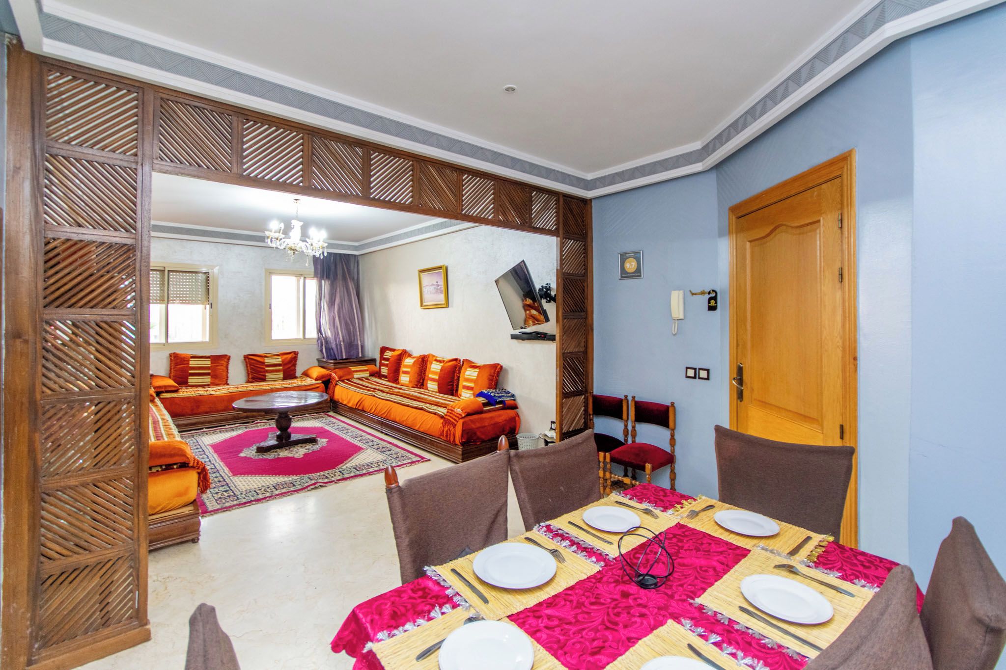 A dining area with a table set for four, a sofa, and a TV in the background.