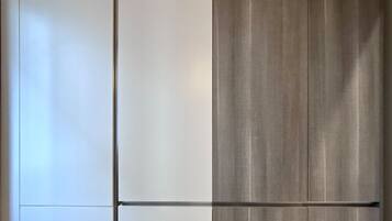 A room with a large wardrobe, a wooden floor, and a plain wall.