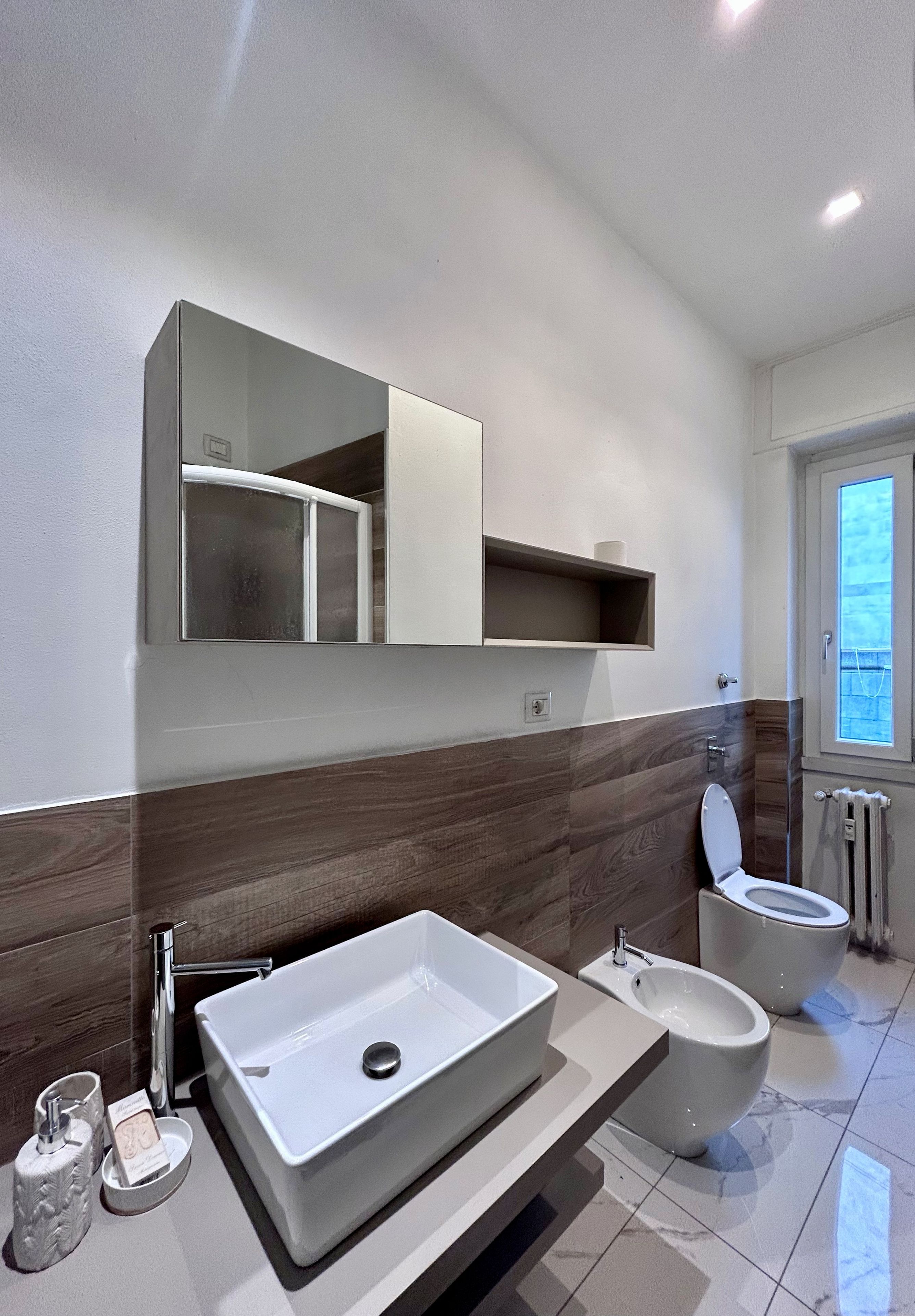 A modern bathroom with a large rectangular sink, a toilet, and a bidet.