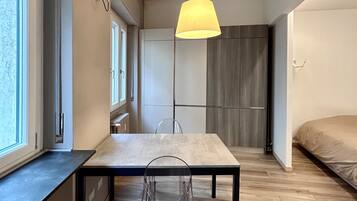 A modern interior with a dining table, chairs, a pendant light, and a bed.