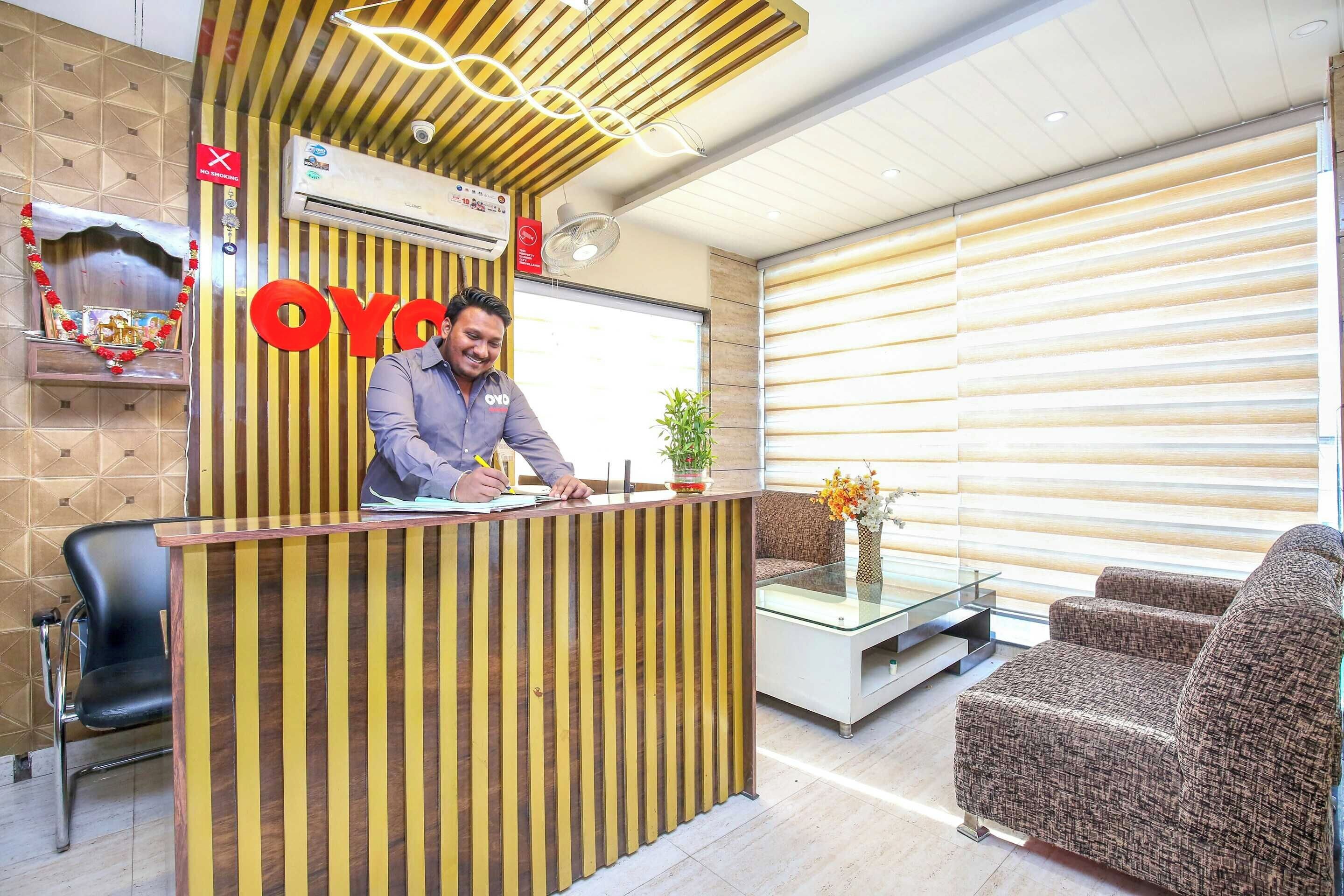 A reception desk with a 'NO SMOKING' sign, a man at the desk, and a modern interior with a sofa and a glass table.