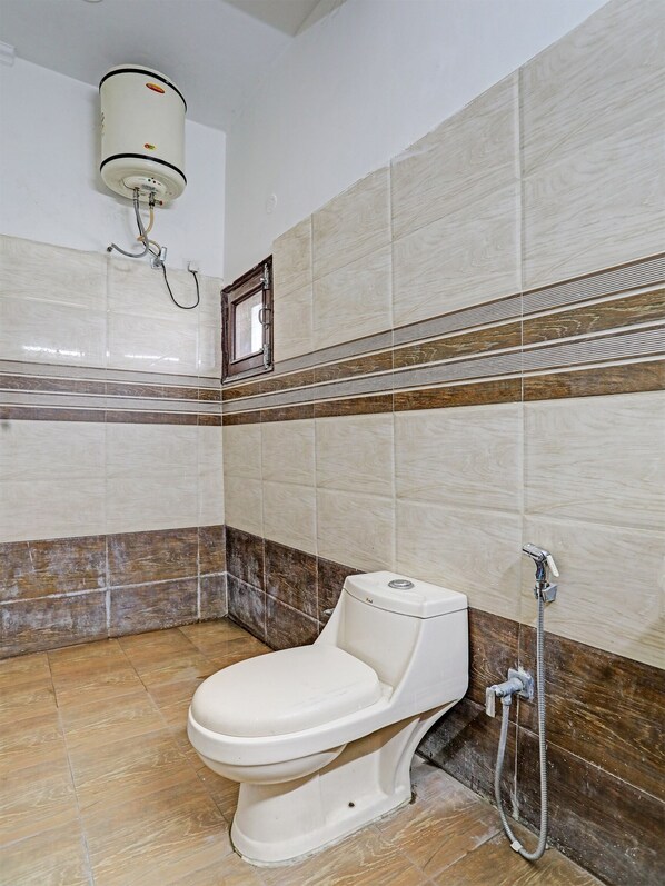 Un baño con inodoro, ducha y calentador de agua instalado en la pared.