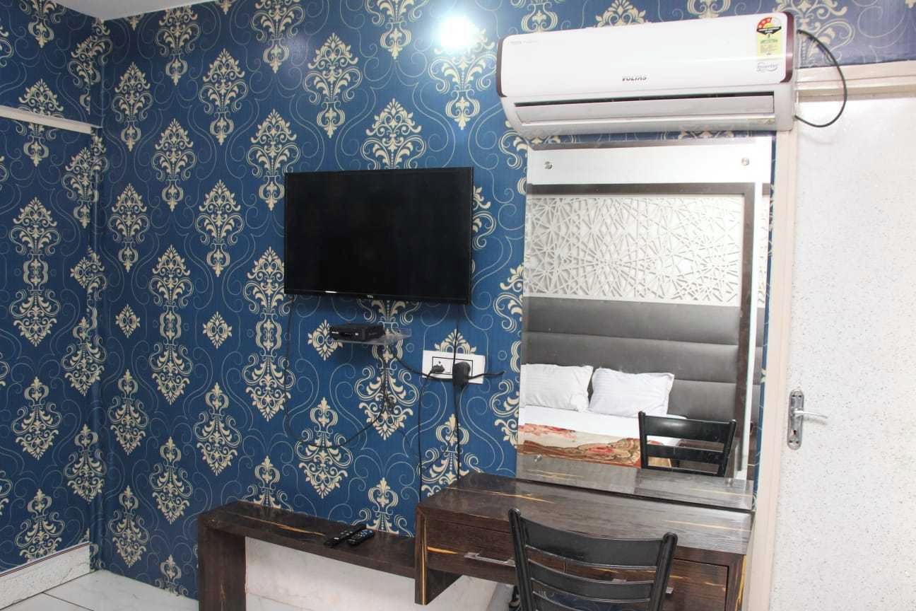 Une chambre d’hôtel équipée d’un lit, d’un bureau, d’une chaise, d’une télévision et d’un appareil de climatisation.