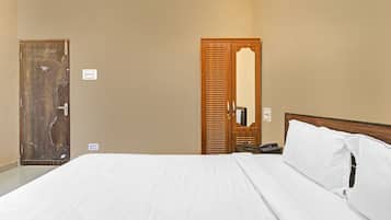 Ein Hotelzimmer mit einem Bett, einer Holztür, einem Spiegel und einem Telefon.