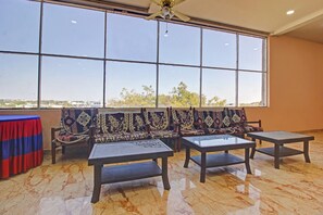 Una habitación con un ventanal grande, ventilador de techo y una mesa con sillas.