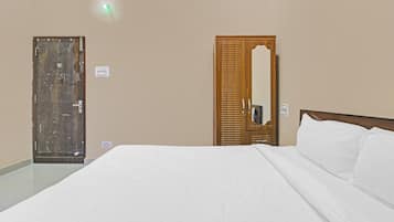 Ein Hotelzimmer mit einem Bett, einem Holzschrank, einem Spiegel und einer Tür.