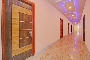 Un pasillo de hotel con piso de mármol, puertas de madera e iluminación empotrada en el techo.
