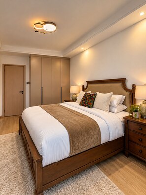 Une chambre à coucher avec un grand lit, des tables de chevet, une armoire et un luminaire au plafond.