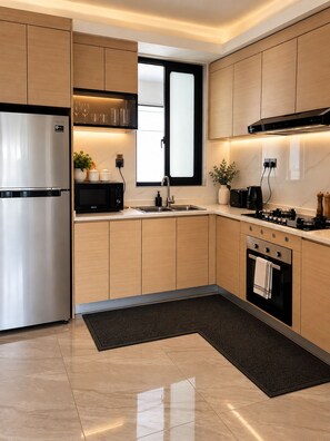Une cuisine moderne équipée d’appareils électroménagers en acier inoxydable, d’un four à micro-ondes noir et d’un évier à deux bacs.