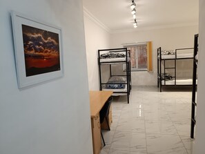 Una camera del dormitorio con letti a castello, una scrivania e un quadro appeso al muro.
