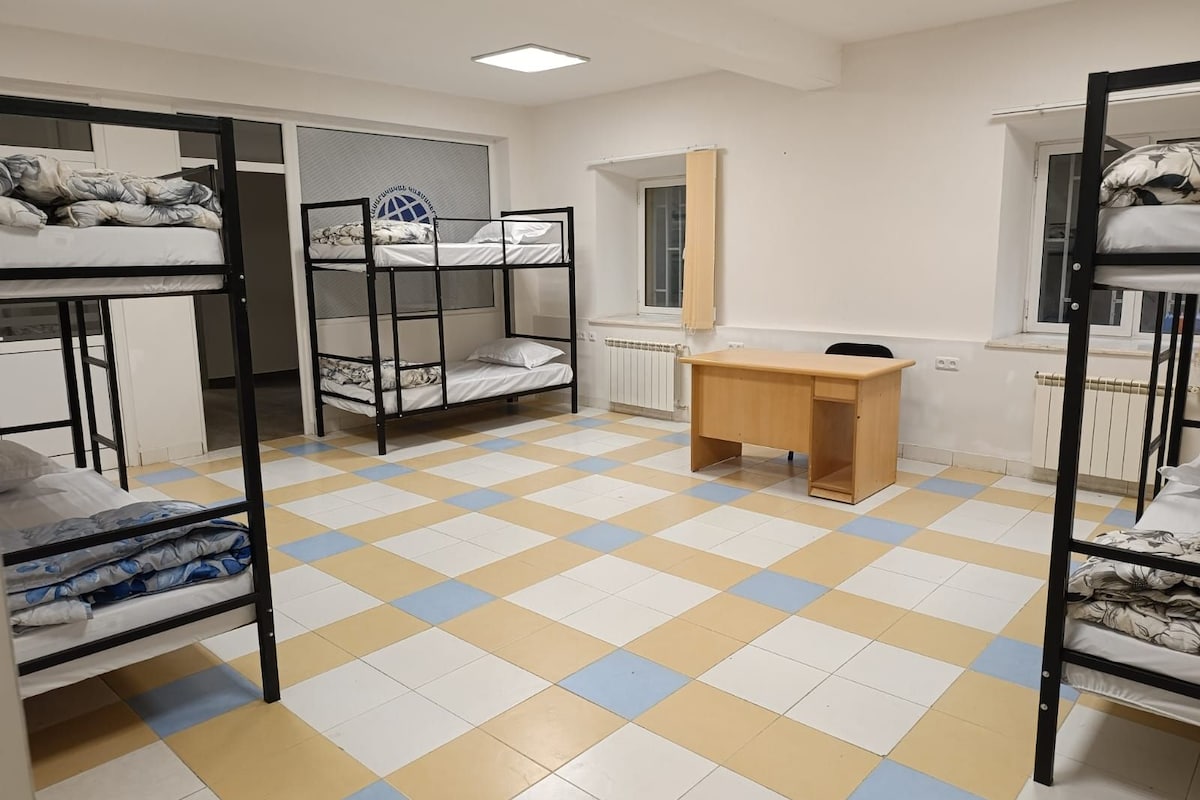 Una camera del dormitorio con letti a castello, una scrivania e una finestra.