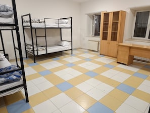 Una camera del dormitorio con letti a castello, una scrivania in legno e un termosifone.