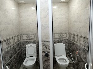 Un bagno con due servizi, pareti in marmo e piastrelle decorative.