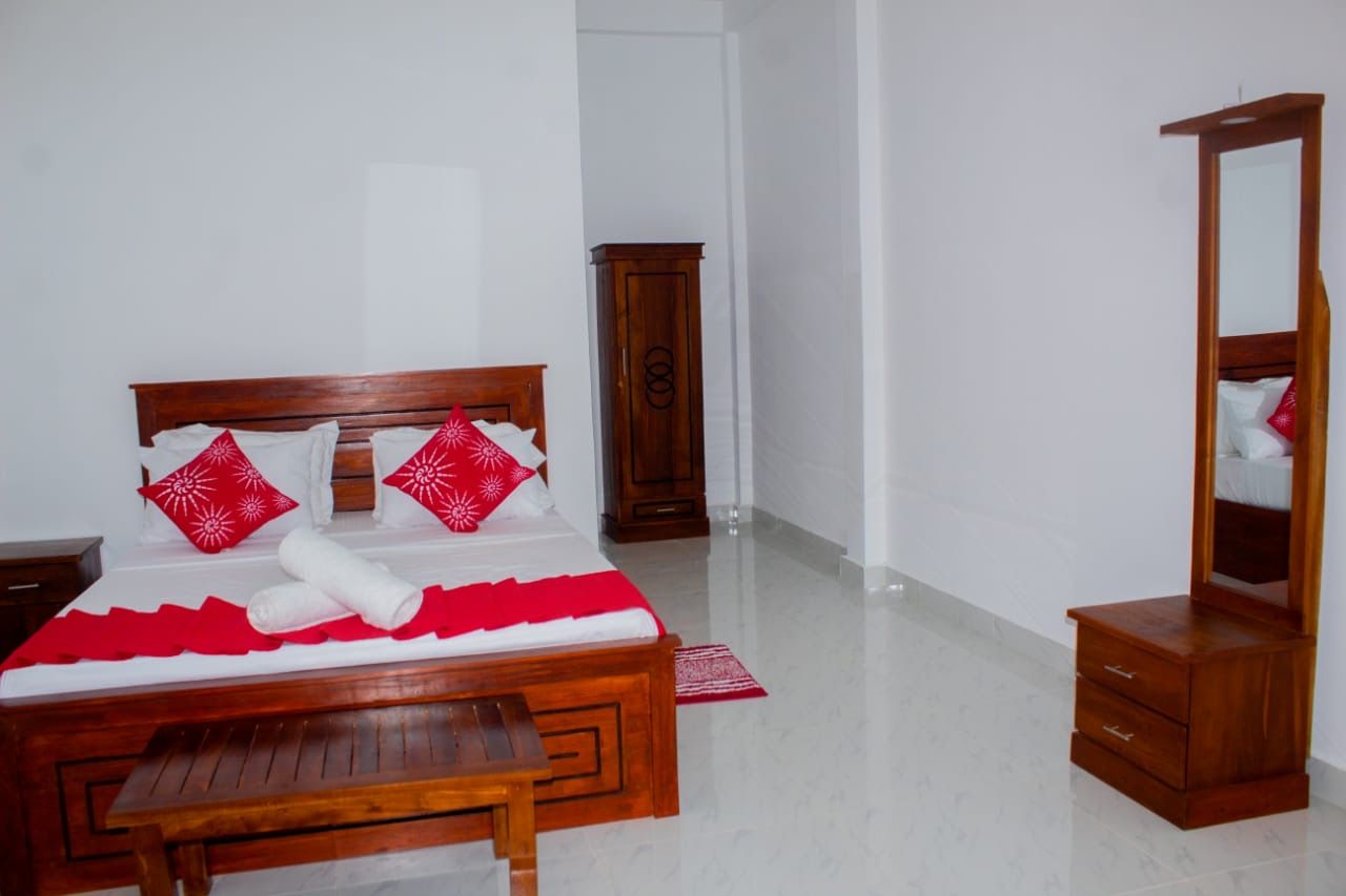 Un dormitorio ordenado con una cama de madera, un aparador y un espejo.