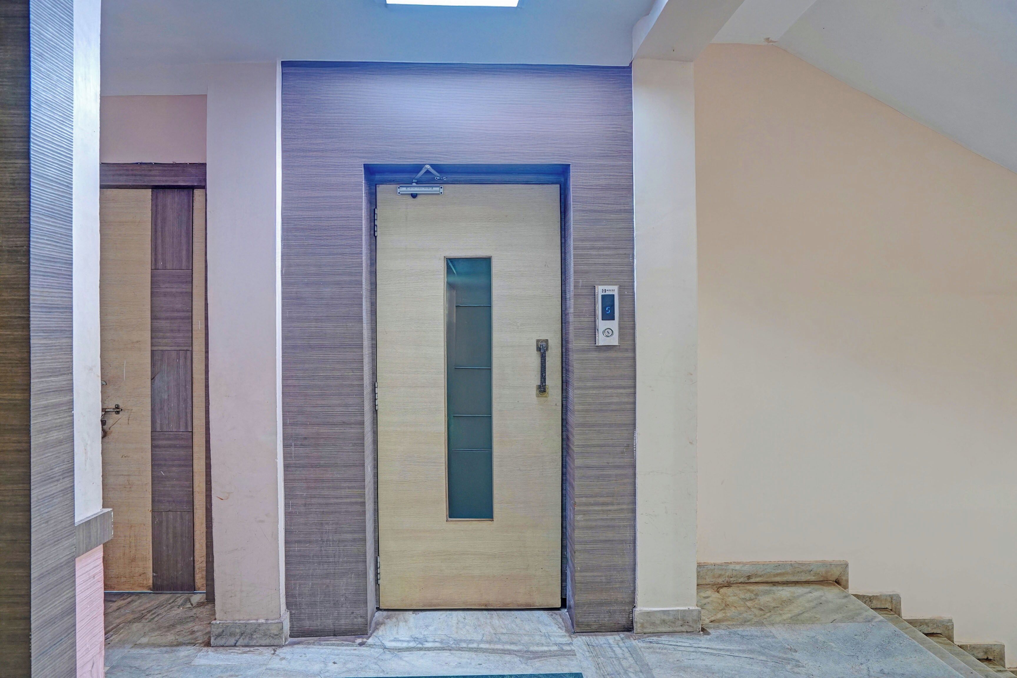 A hallway with a closed door, a small window, and a staircase leading to an upper floor.