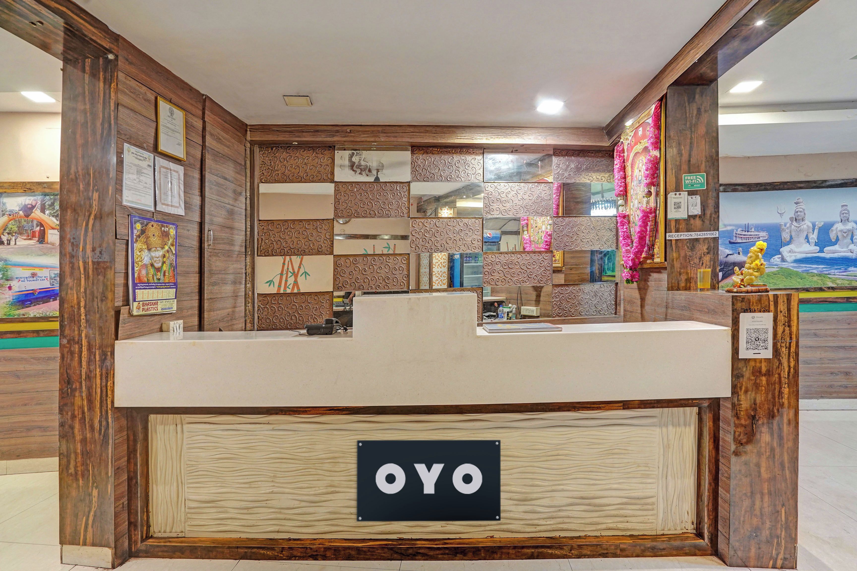 A reception desk with a sign reading 'OYO' in a hotel lobby with wooden paneling and decorative tiles.