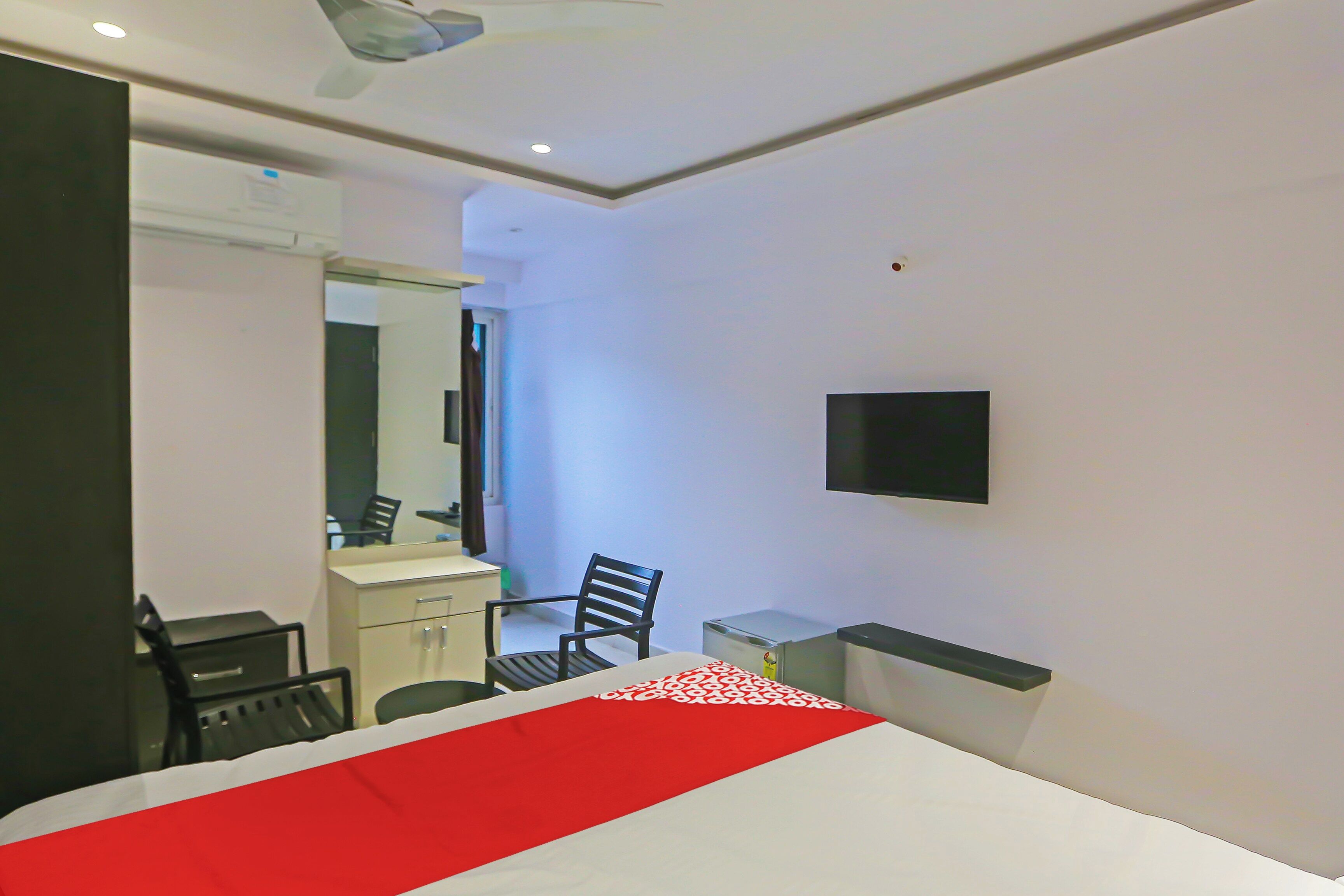 A hotel room with a bed, a desk, a chair, a television, and a mirror.