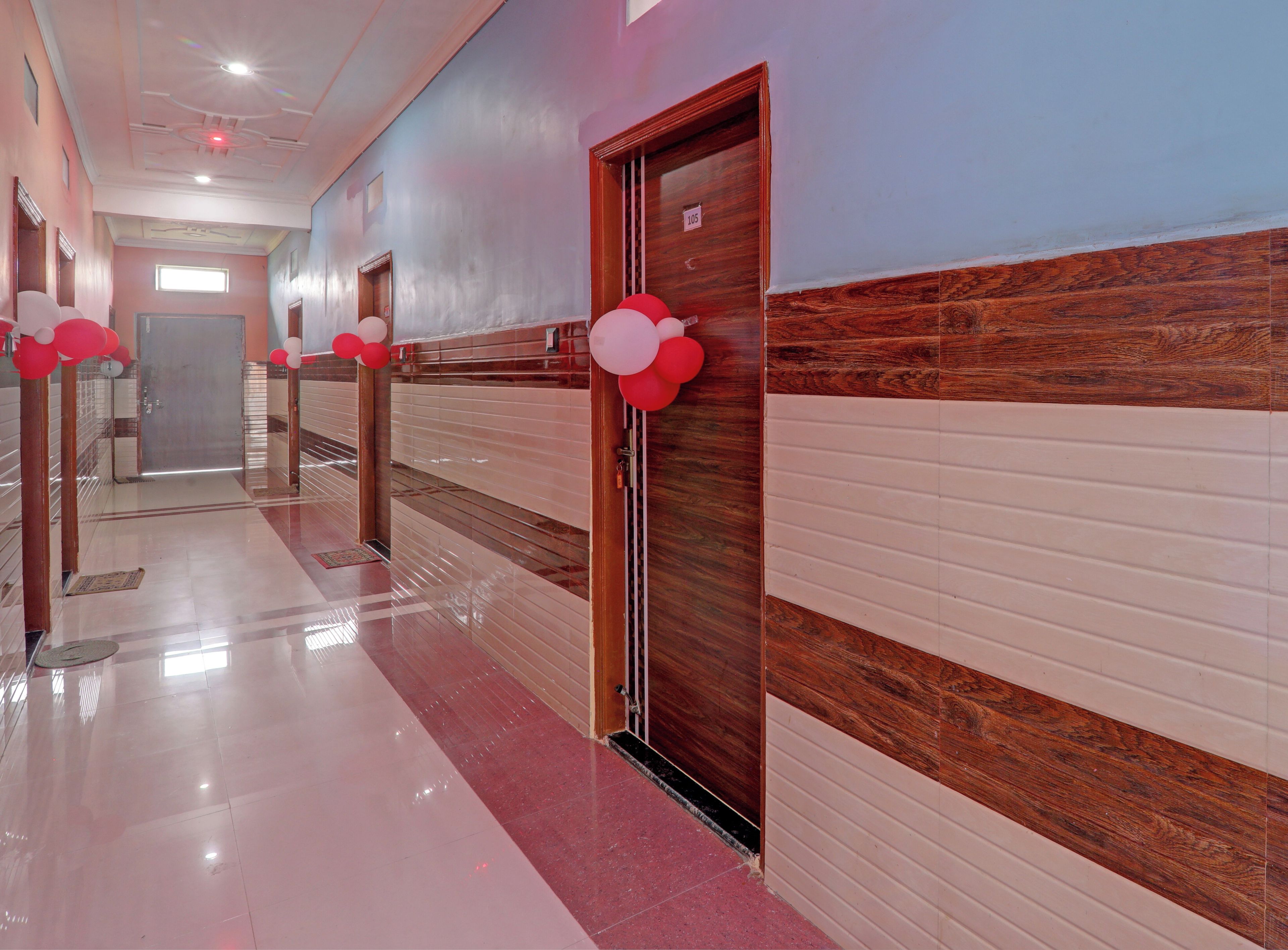 A hotel corridor with a shiny tiled floor, wooden doors, and a number sign on one door.