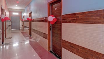 A hotel corridor with a shiny tiled floor, wooden doors, and a number sign on one door.
