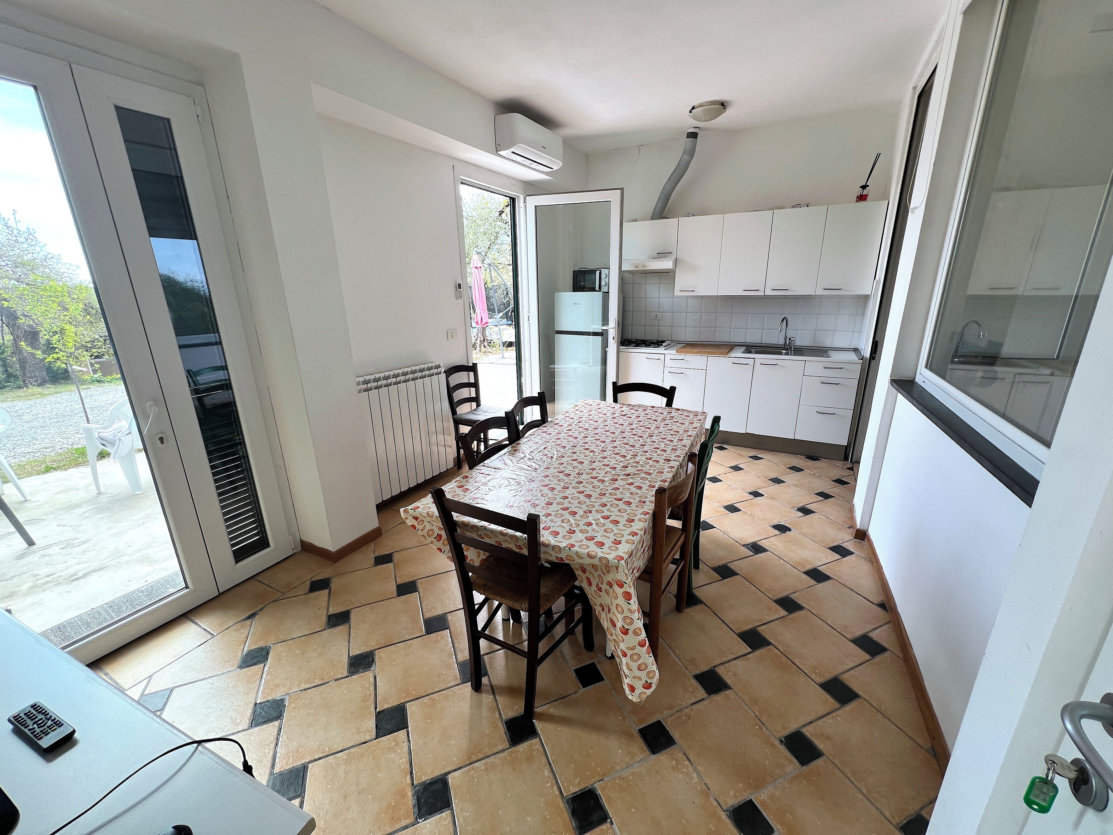 Una cucina compatta con zona pranzo, un termosifone e vista attraverso la porta.