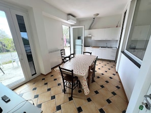 A compact kitchen with a dining area, a radiator, and a view through the door. - Appartamento Venere in Villa Daria (Chiavari)