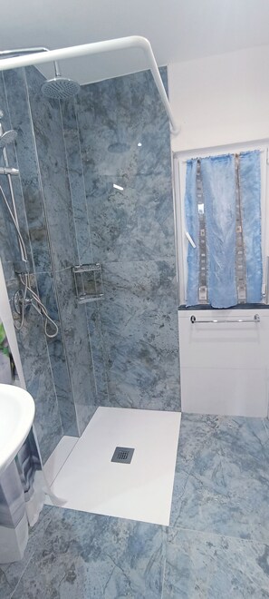 A bathroom with a shower, a sink, and a window with a view of a building. - Appartamento Venere in Villa Daria (Chiavari)