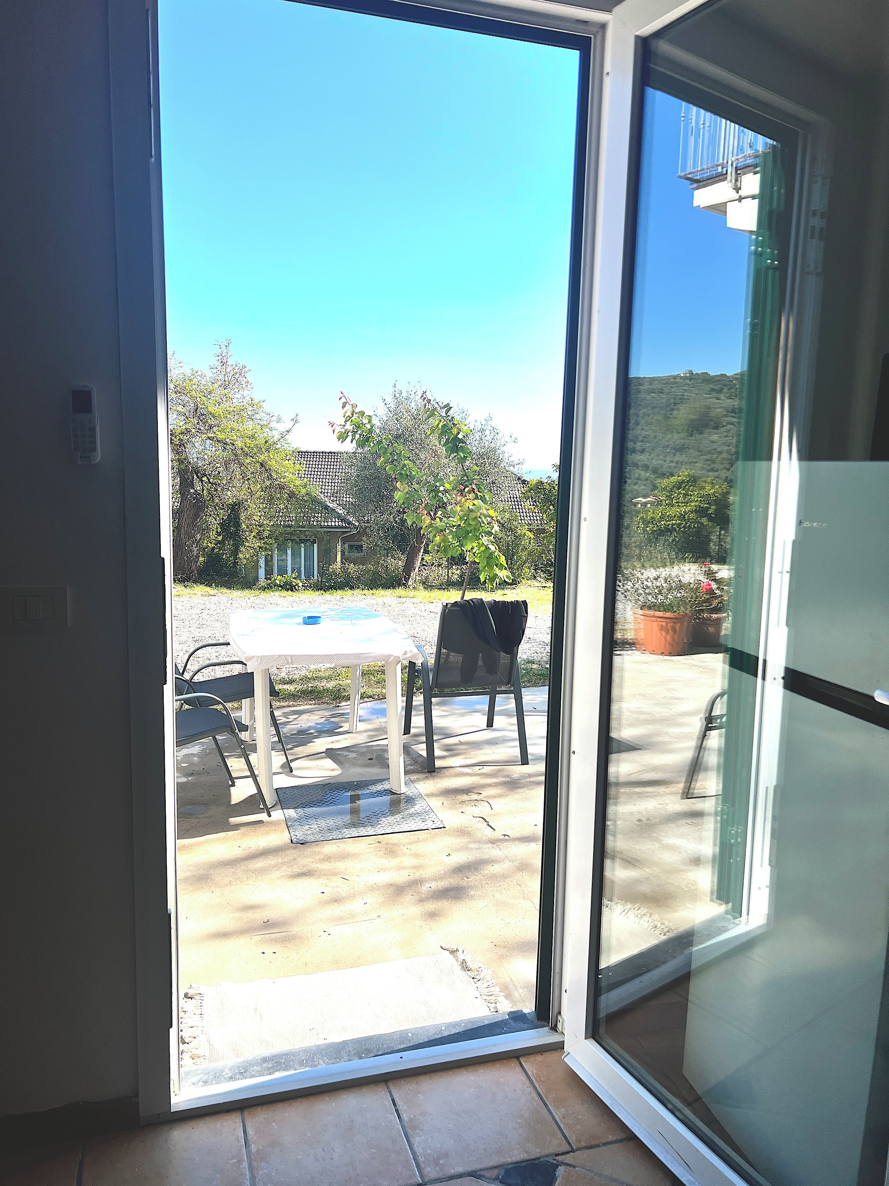 Eine Glastür führt zu einer Terrasse mit Tisch und Stühlen.