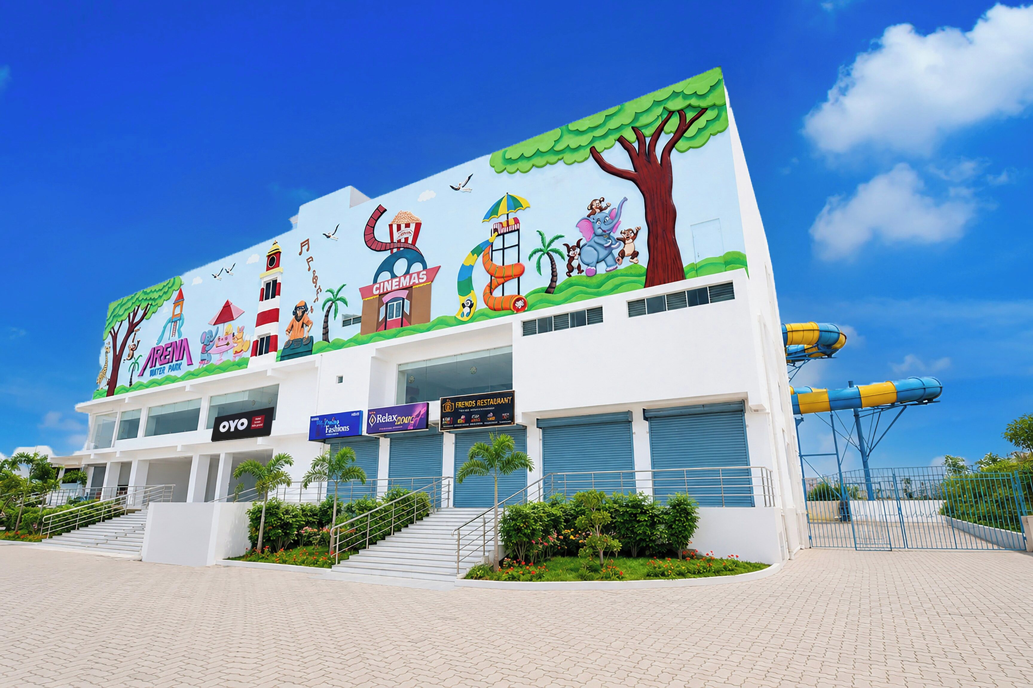 A building with a colorful mural, a water slide, and multiple business signs including a cinema and a restaurant.