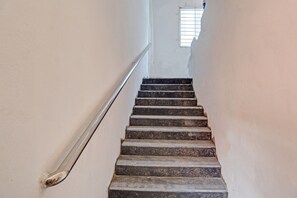 Una escalera con barandilla metálica que sube hasta una ventana.