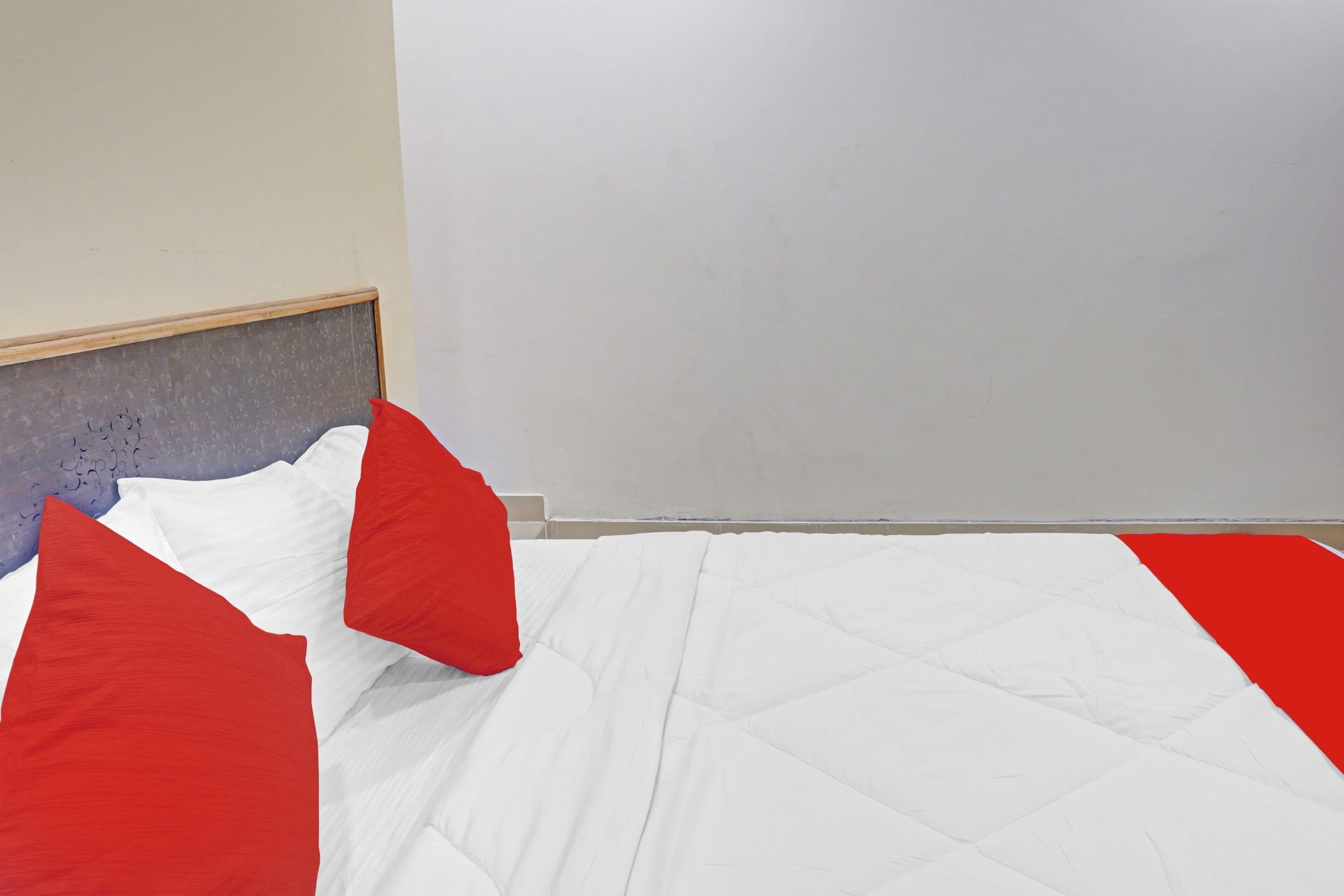 A room with a bed, a headboard, and a plain wall.