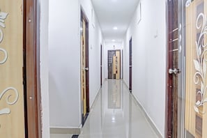 Un pasillo con puertas a ambos lados, suelo de baldosas y un accesorio de iluminación en el techo.