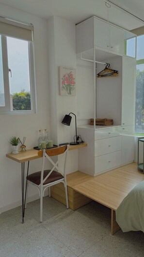 Un dormitorio con escritorio, silla, armario y ventana.
