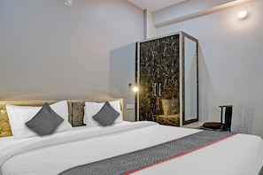 A modern hotel room with a large bed, a wardrobe with a marble-like finish, and a bedside table with a lamp. - Hotel O Navneeta Grand (Varanasi)