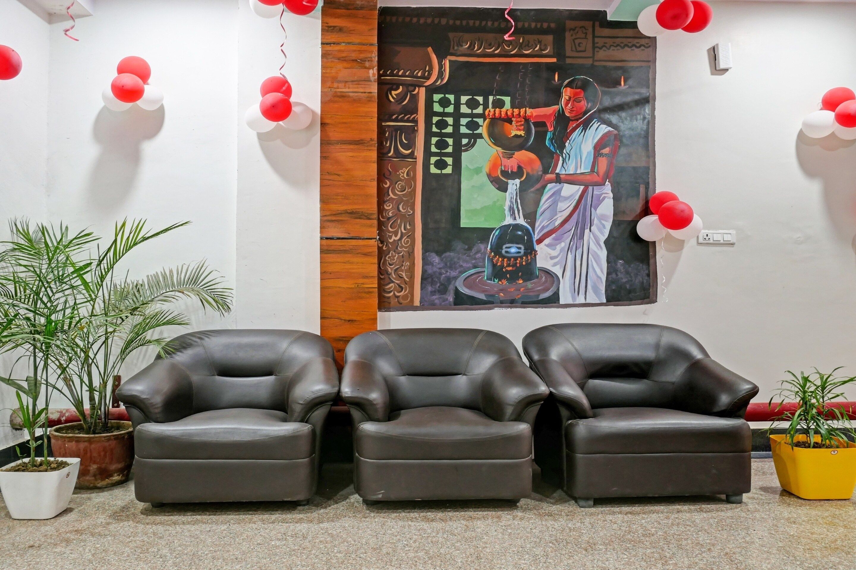 A room with three leather chairs, a wall mural, and potted plants.