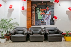 A room with three leather chairs, a wall mural, and potted plants. - Hotel O Navneeta Grand (Varanasi)