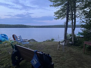 Un endroit au bord du lac avec un banc, des chaises et un kayak.