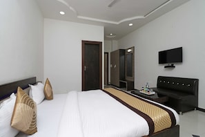Quarto de hotel com cama grande, televisão de tela plana, sofá e escrivaninha com bandeja de lanches.